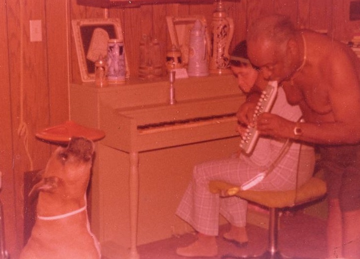 Basie, Diane and dog around a piano